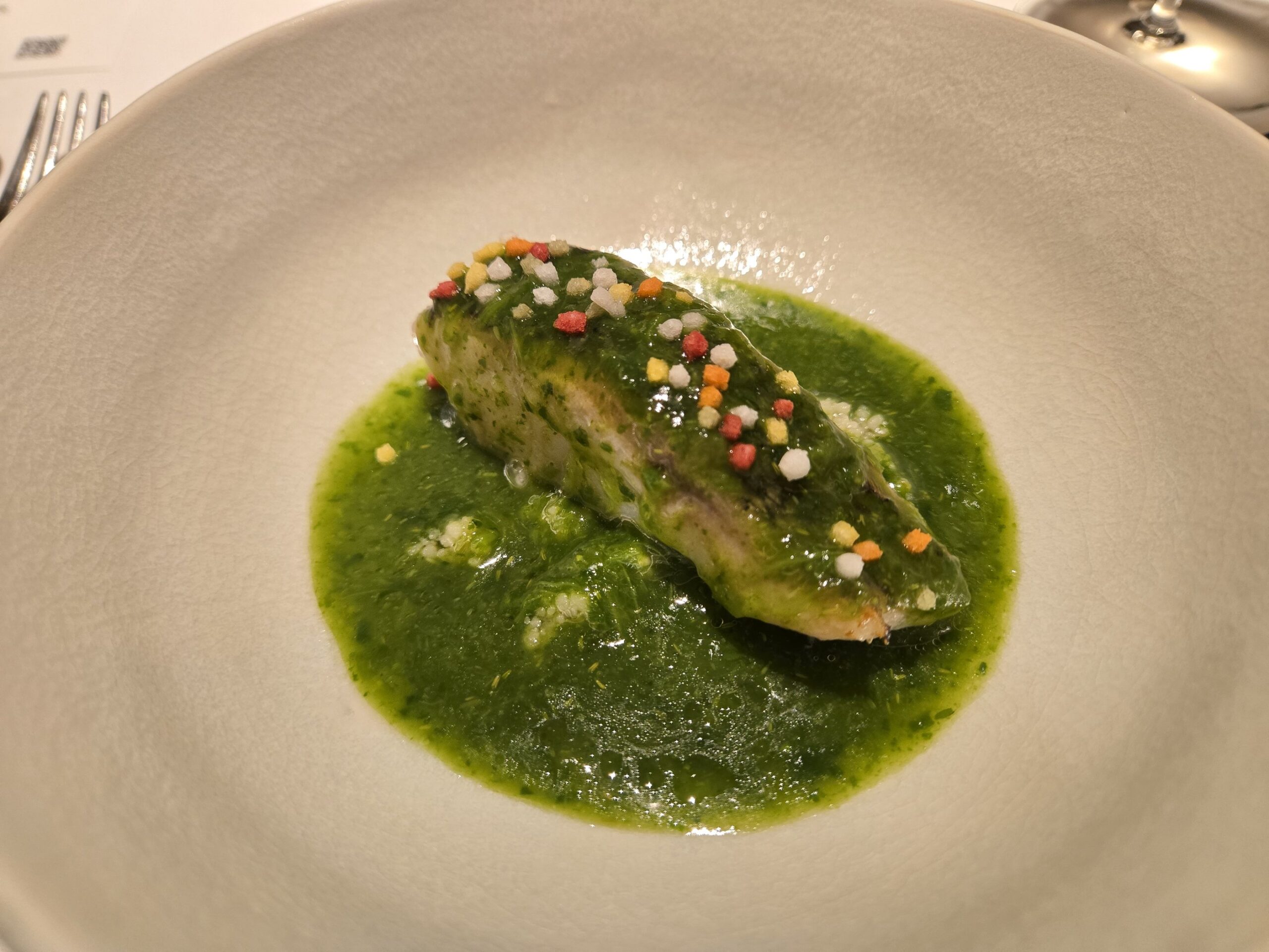 緑のソースとカラフルな飾りの魚料理