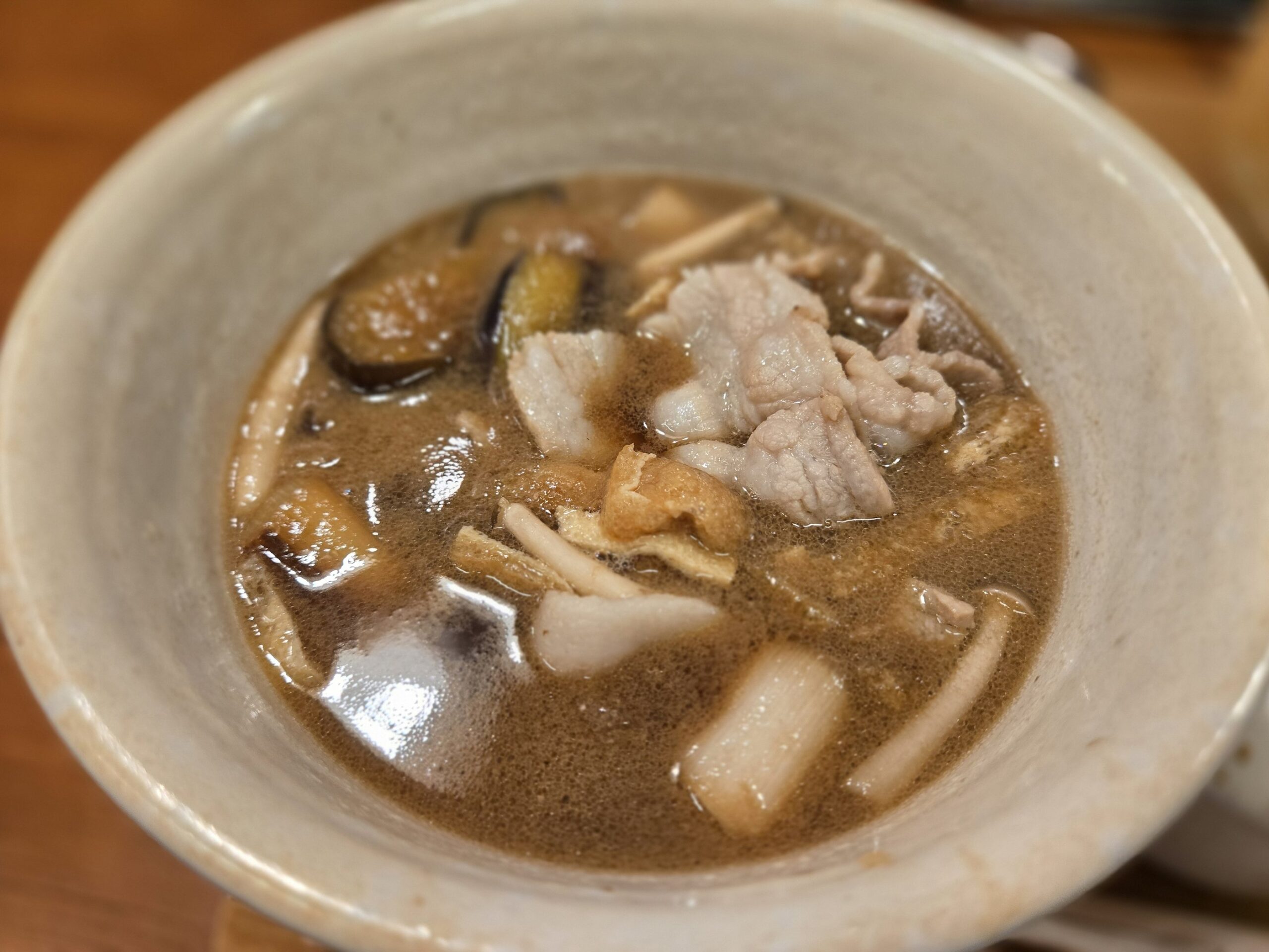 豚肉と野菜入りのつけ汁が陶器の器に盛られている