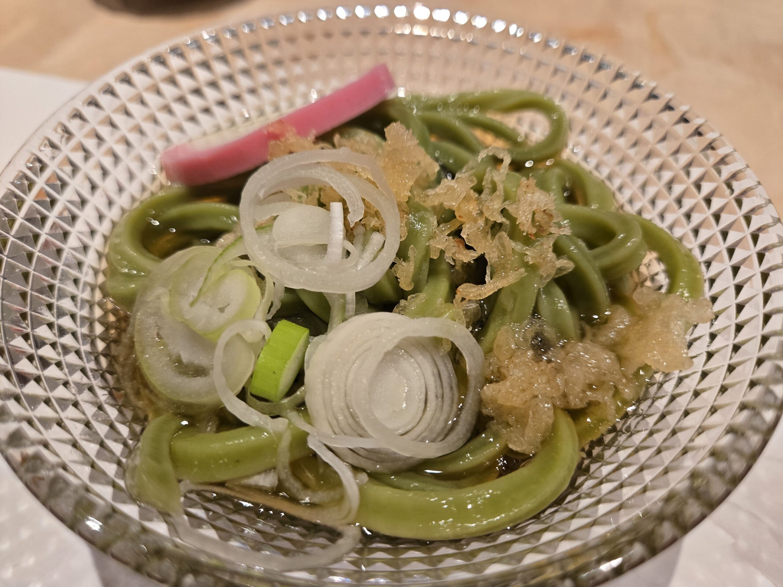 抹茶そばにカマボコが添えられている