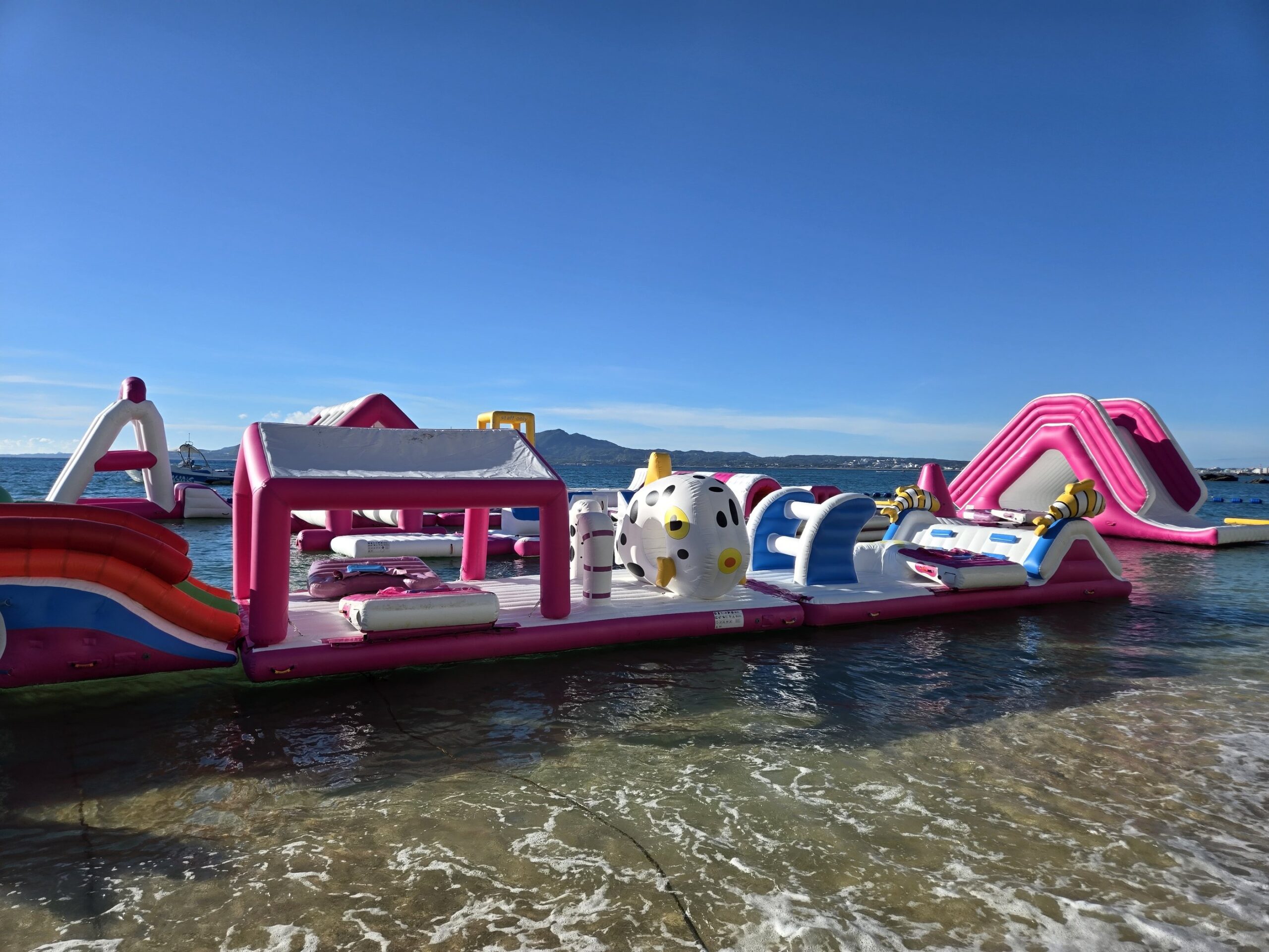 海にあるピンクと白の水上アスレチック