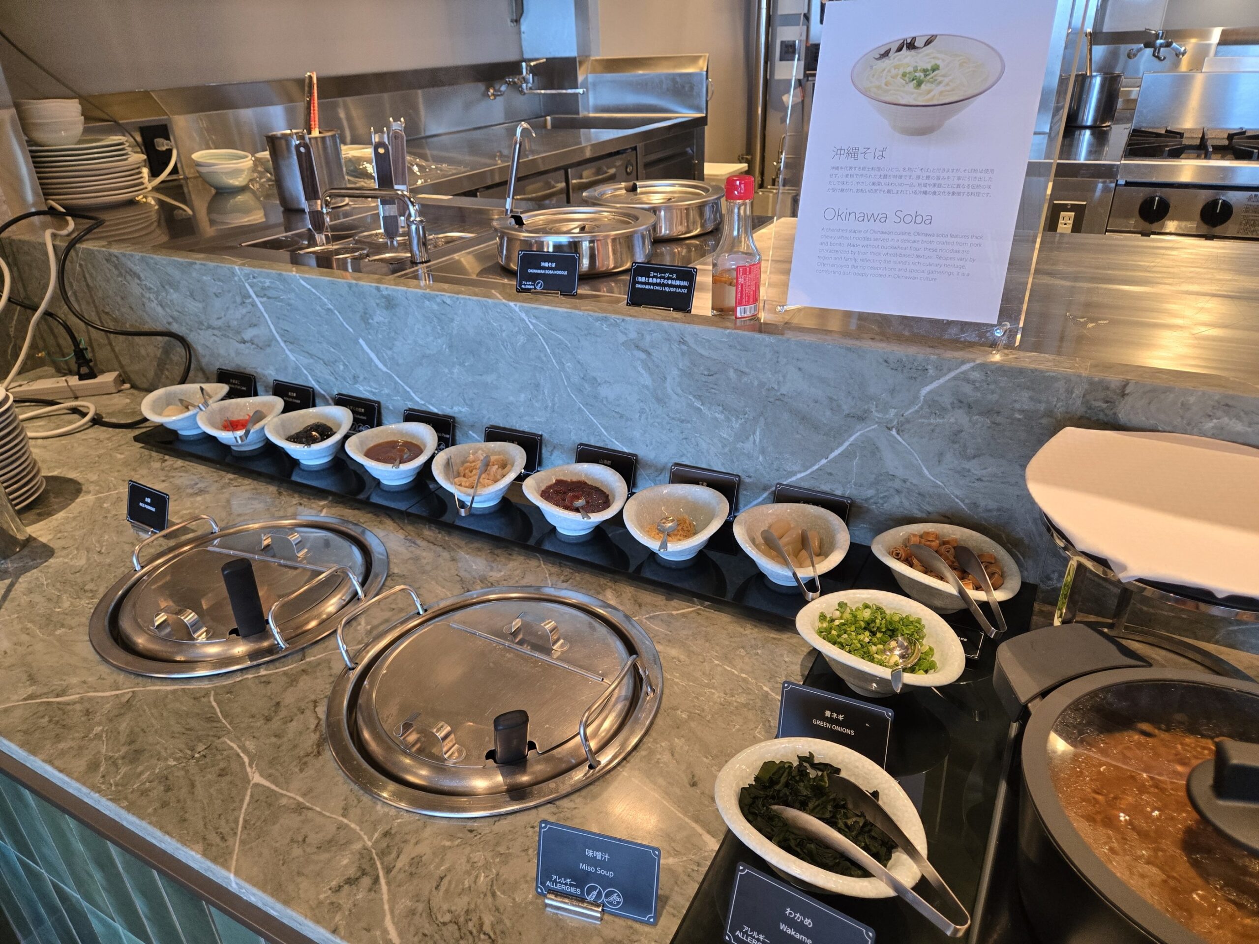 ホテル朝食ビュッフェの温菜コーナー、オキナワそばや他の料理が並ぶ