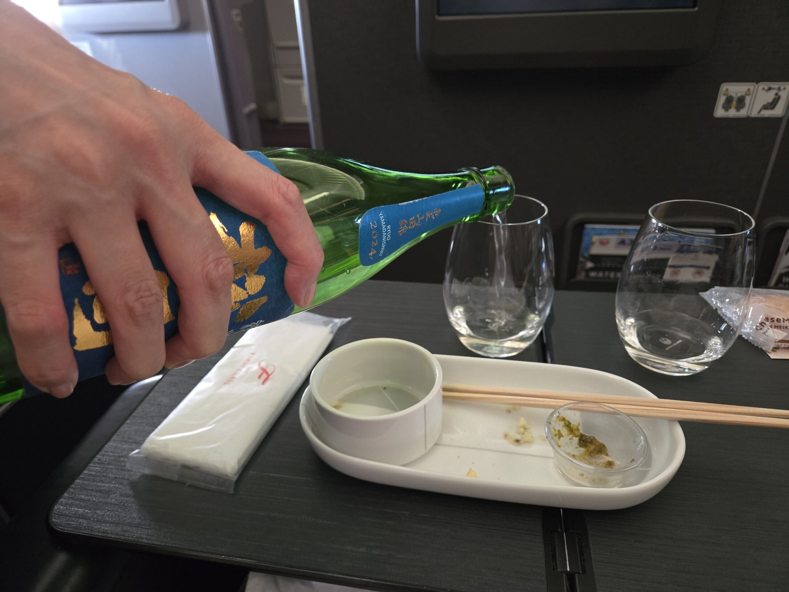 JAL機内で日本酒の松の司をグラスに注ぐ様子
