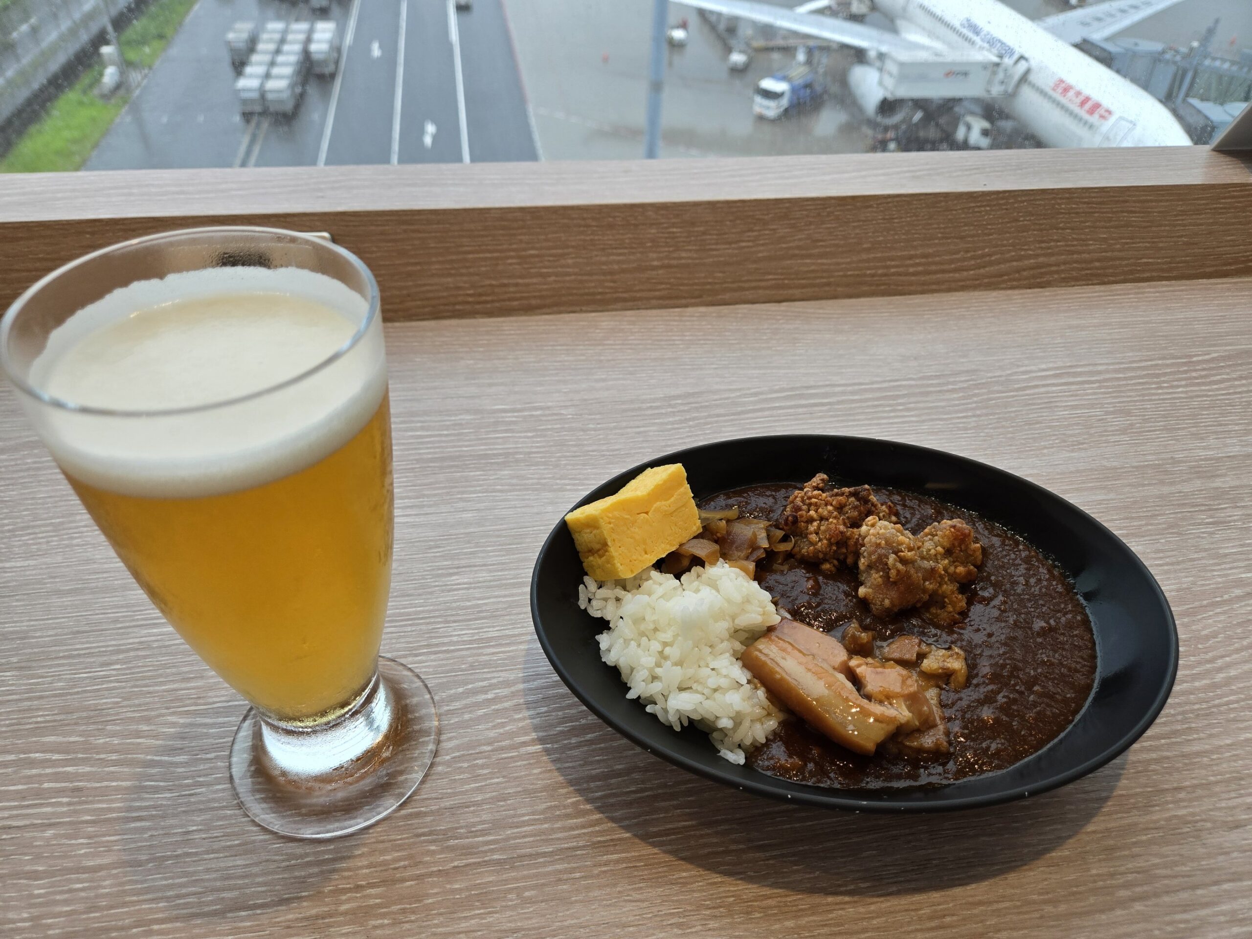 飛行機を背景にしたカレーとビール