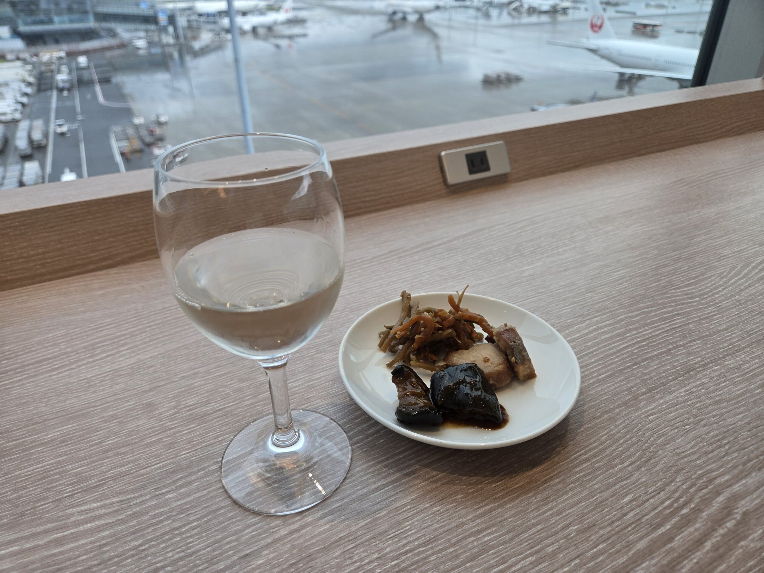 空港ラウンジの窓際席の日本酒と食事