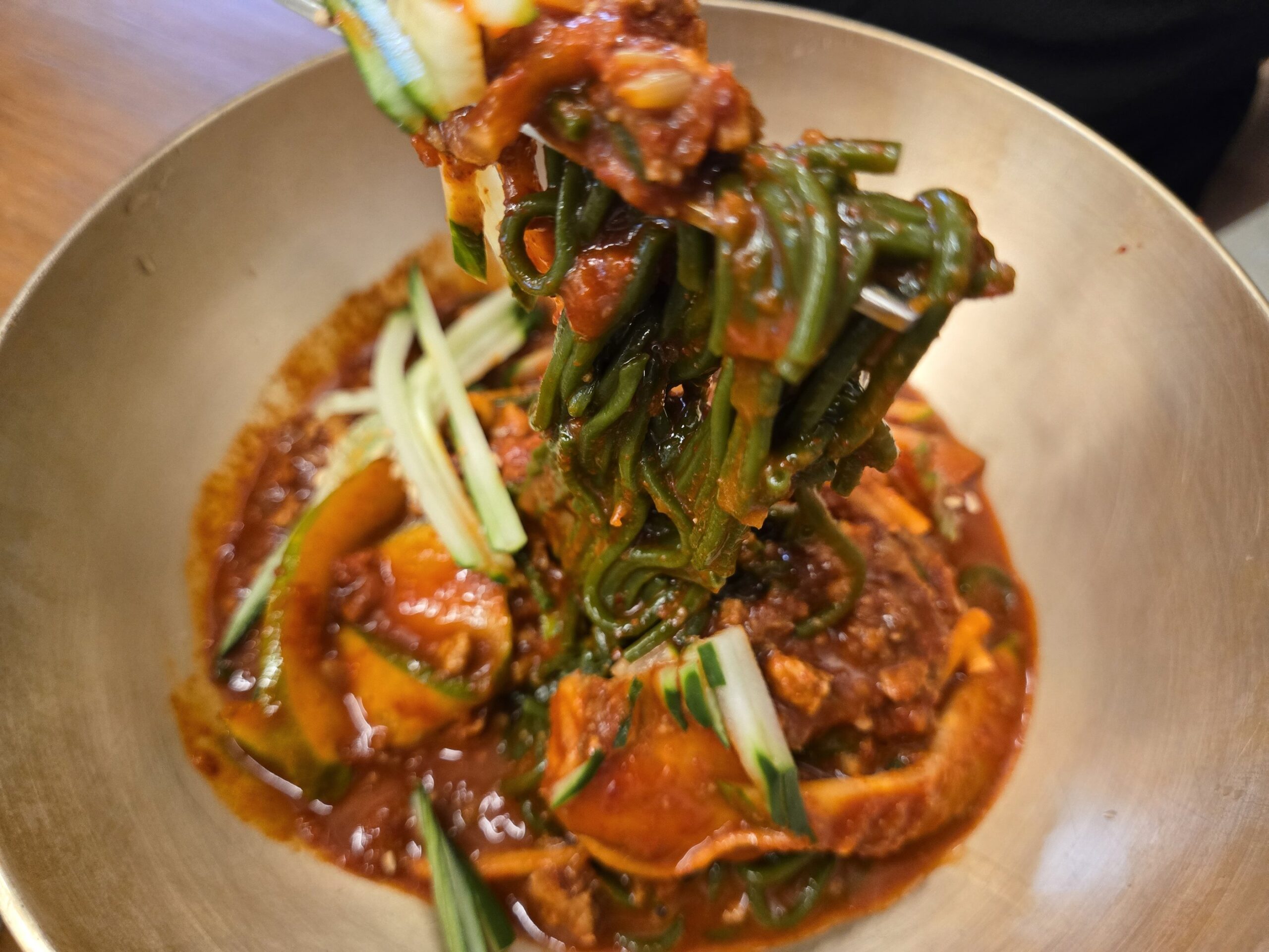 タレに絡んだ緑色の麺