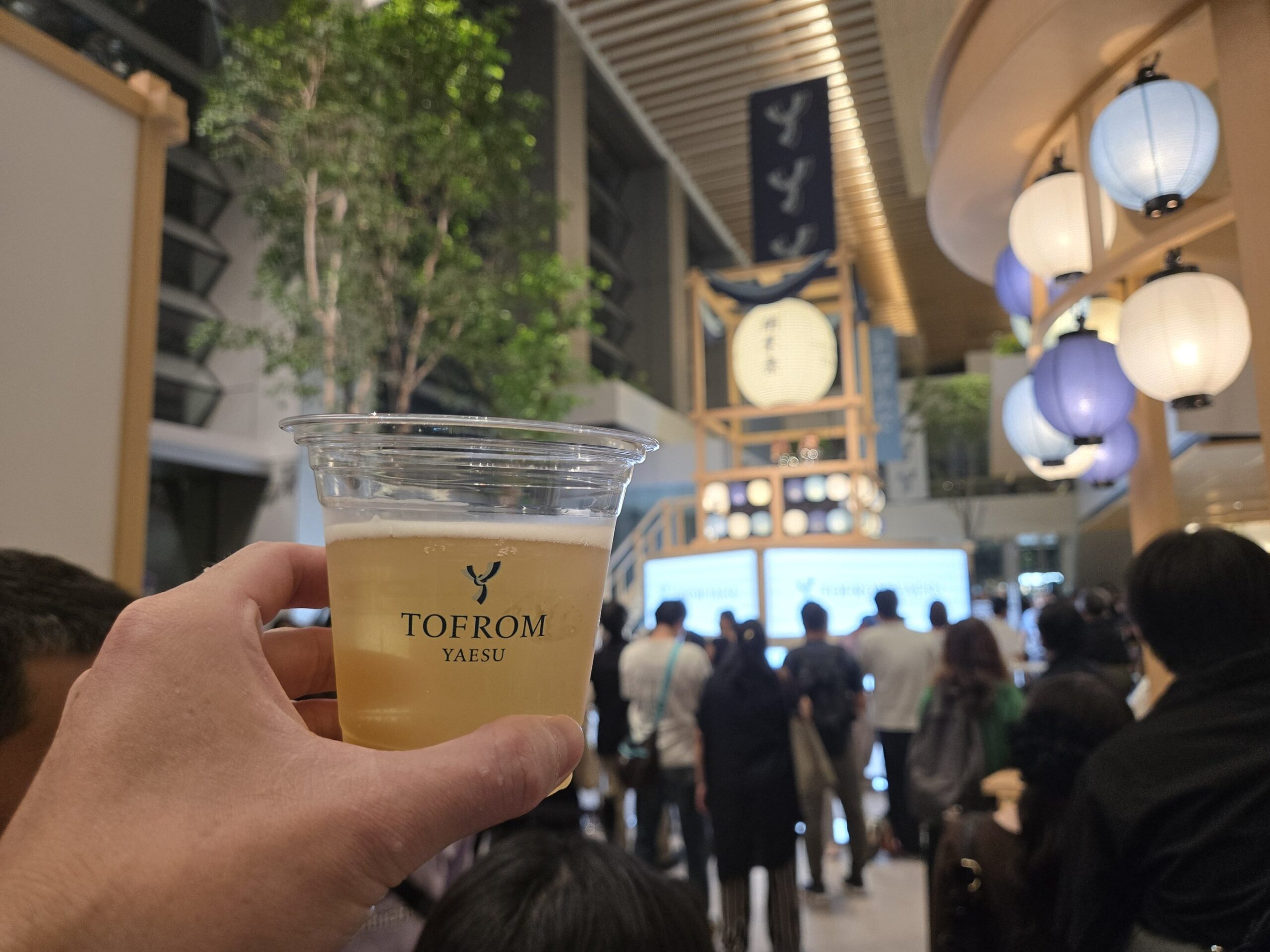 TOFROM YAESUのオープンイベントで1杯無料のビールを手にした様子